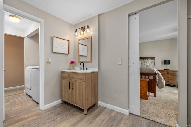 2106 Bayside Ct, Fort Wayne, IN 46804 - ensuite bathroom featuring wood finished floors, washing machine and dryer, vanity, and baseboards