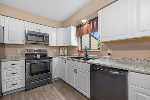 2106 Bayside Ct, Fort Wayne, IN 46804 - kitchen with stainless steel appliances, a sink, white cabinets, and wood finished floors