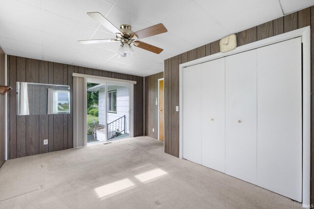5460 N 550 E, Churubusco, IN 46723 - unfurnished bedroom featuring wooden walls, carpet floors, access to outside, a closet, and a ceiling fan