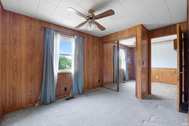 5460 N 550 E, Churubusco, IN 46723 - unfurnished bedroom featuring multiple windows, carpet flooring, wood walls, ceiling fan, and a closet