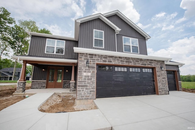 909 S Hoke Ave, Frankfort, IN 46041 - view of front facade with board and batten siding, french doors, stone siding, and concrete driveway
