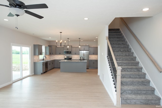 909 S Hoke Ave, Frankfort, IN 46041 - kitchen with gray cabinetry, stainless steel appliances, a sink, decorative backsplash, and light wood-style flooring