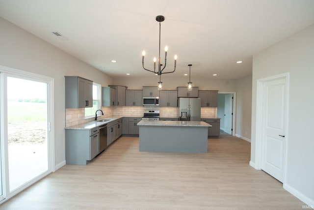 909 S Hoke Ave, Frankfort, IN 46041 - kitchen with stainless steel appliances, gray cabinets, a chandelier, tasteful backsplash, and a center island