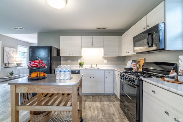 807 W Washington Blvd, Fort Wayne, IN 46802 - kitchen with black appliances, a sink, light wood-style floors, light countertops, and white cabinetry