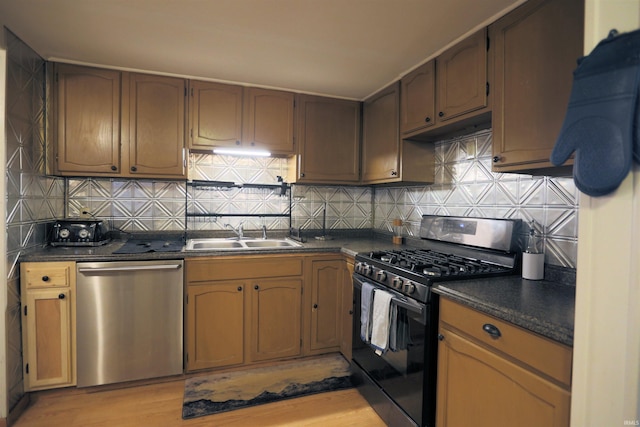 482 E Jefferson St, Andrews, IN 46702 - kitchen featuring appliances with stainless steel finishes, a sink, dark countertops, light wood finished floors, and tasteful backsplash