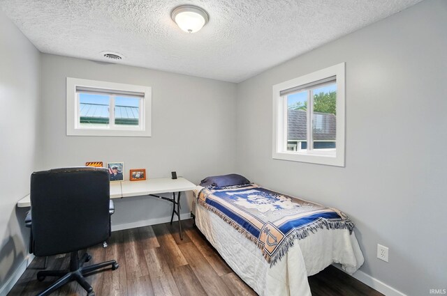 202 E Pickwick Dr, Syracuse, IN 46567 - bedroom with dark wood-type flooring, baseboards, a textured ceiling, and a desk