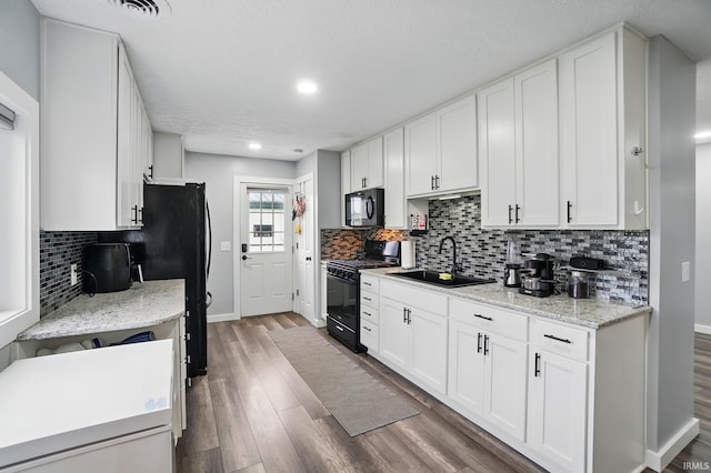 202 E Pickwick Dr, Syracuse, IN 46567 - kitchen with black appliances, a sink, baseboards, white cabinets, and wood finished floors