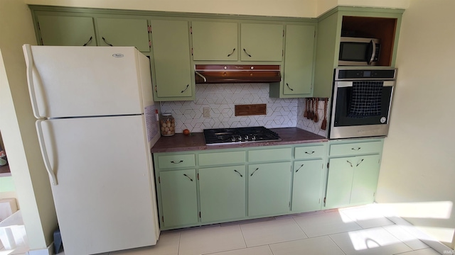 6403 Old Trail Rd, Fort Wayne, IN 46809 - kitchen with appliances with stainless steel finishes, under cabinet range hood, tasteful backsplash, dark countertops, and green cabinets