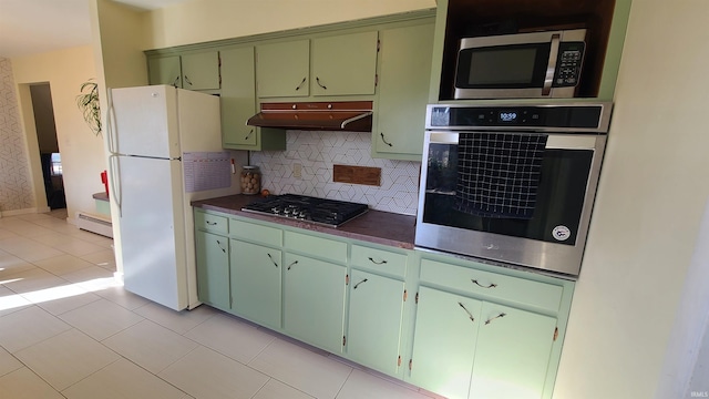 6403 Old Trail Rd, Fort Wayne, IN 46809 - kitchen featuring appliances with stainless steel finishes, under cabinet range hood, baseboard heating, dark countertops, and green cabinetry