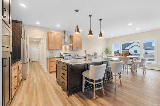2088 Seward Lake Pass, Fort Wayne, IN 46814 - kitchen featuring wall chimney exhaust hood, light brown cabinets, a kitchen breakfast bar, dark countertops, and light wood finished floors