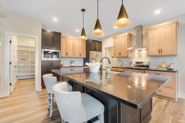2088 Seward Lake Pass, Fort Wayne, IN 46814 - kitchen featuring stainless steel appliances, wall chimney range hood, dark countertops, a sink, and light wood finished floors
