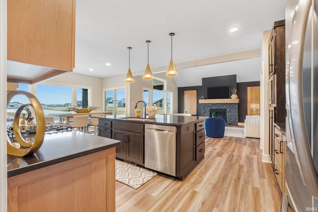 2088 Seward Lake Pass, Fort Wayne, IN 46814 - kitchen featuring appliances with stainless steel finishes, dark countertops, a sink, a stone fireplace, and open floor plan
