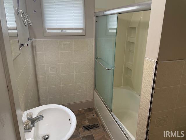 3007 S Hackley St, Muncie, IN 47302 - full bathroom featuring tile walls, shower / bath combination with glass door, a sink, and a wainscoted wall