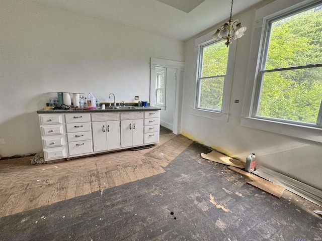 806 E Market St, Logansport, IN 46947 - kitchen featuring dark countertops, white cabinetry, hanging light fixtures, and a sink