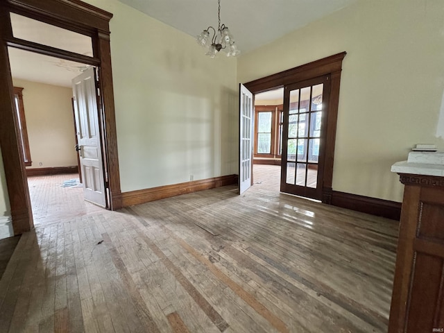 806 E Market St, Logansport, IN 46947 - unfurnished dining area with wood-type flooring, a chandelier, and baseboards
