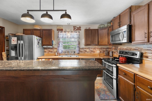 3739 S Westmont Ave, Bloomington, IN 47403 - kitchen featuring appliances with stainless steel finishes, a sink, decorative backsplash, pendant lighting, and dark stone countertops