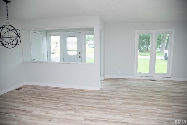 1105 W Tilmor Dr, Muncie, IN 47303 - spare room with a chandelier, plenty of natural light, light wood-type flooring, and baseboards