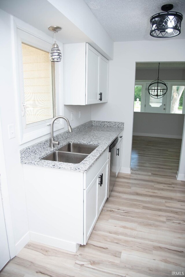 1105 W Tilmor Dr, Muncie, IN 47303 - kitchen featuring a sink, stainless steel dishwasher, white cabinetry, light wood-style flooring, and a textured ceiling