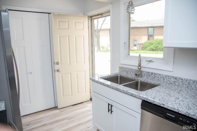 1105 W Tilmor Dr, Muncie, IN 47303 - kitchen with appliances with stainless steel finishes, a sink, white cabinetry, light wood finished floors, and light stone countertops