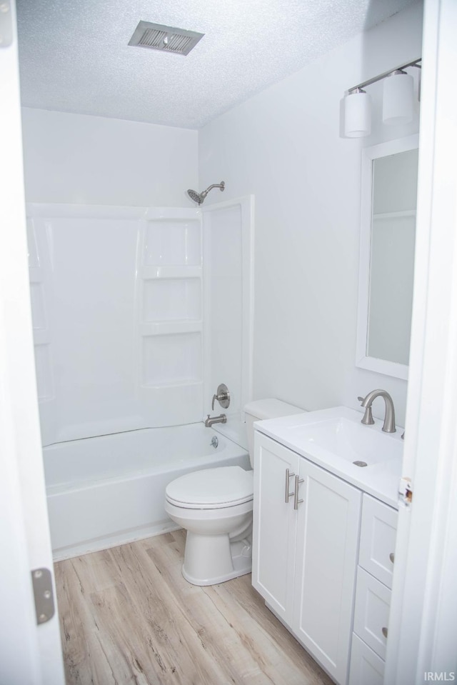 1105 W Tilmor Dr, Muncie, IN 47303 - full bath with wood finished floors, toilet, vanity, a textured ceiling, and  shower combination
