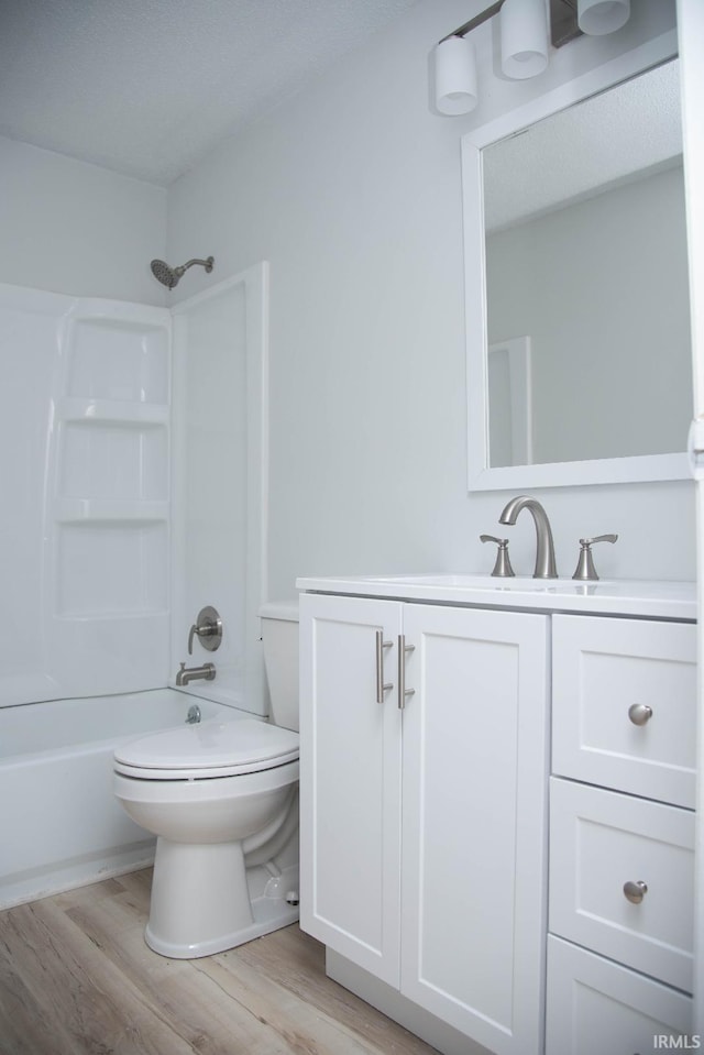 1105 W Tilmor Dr, Muncie, IN 47303 - bathroom with toilet, vanity, wood finished floors, and washtub / shower combination