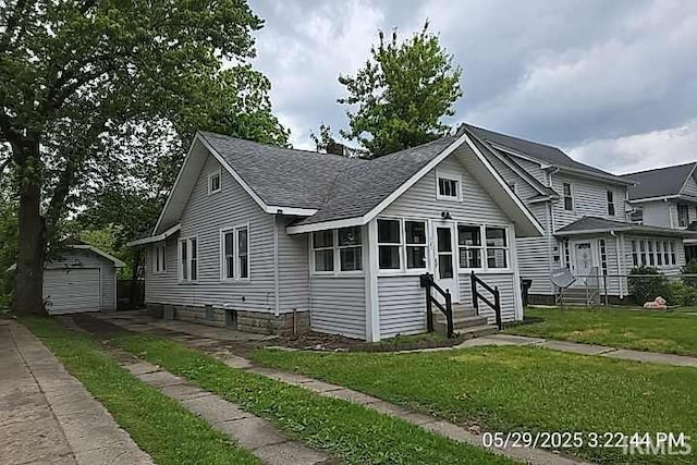 121 Altgeld St, South Bend, IN 46614 - view of front of house featuring entry steps, roof with shingles, a detached garage, an outbuilding, and a front lawn