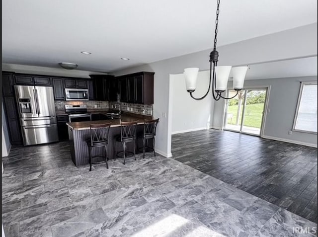 3981 Gussie Ct, Warsaw, IN 46582 - kitchen featuring stainless steel appliances, open floor plan, a sink, dark countertops, and tasteful backsplash