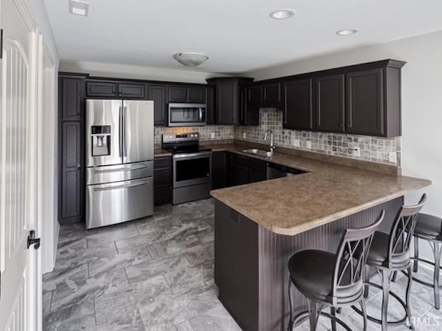 3981 Gussie Ct, Warsaw, IN 46582 - kitchen featuring appliances with stainless steel finishes, a sink, tasteful backsplash, a peninsula, and recessed lighting