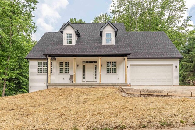 2075 N Russell Rd, Bloomington, IN 47408 - cape cod house featuring a porch, an attached garage, concrete driveway, and a shingled roof