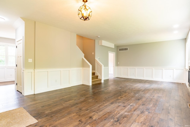 2075 N Russell Rd, Bloomington, IN 47408 - unfurnished living room featuring stairway, wood-type flooring, a wainscoted wall, and a decorative wall