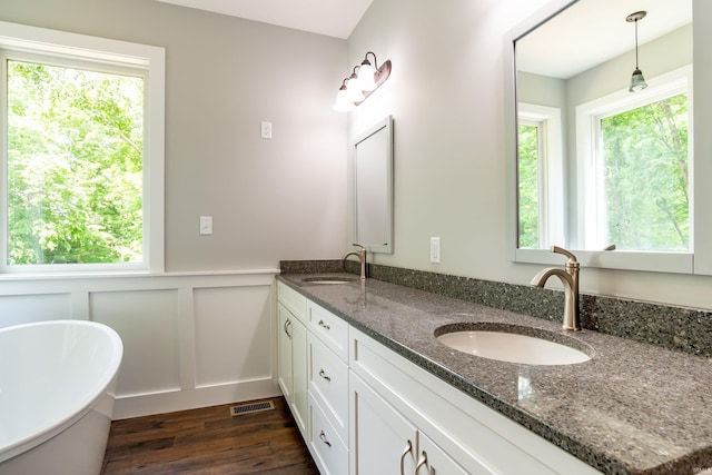 2075 N Russell Rd, Bloomington, IN 47408 - full bath featuring double vanity, wood finished floors, a soaking tub, a decorative wall, and plenty of natural light