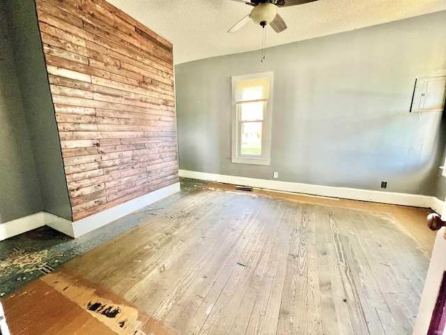 216 W Walnut St, Boonville, IN 47601 - unfurnished room featuring hardwood / wood-style floors, a ceiling fan, baseboards, a textured ceiling, and wood walls