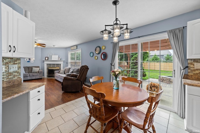 2034 Windflower Pl, West Lafayette, IN 47906 - dining area with a tile fireplace, light tile patterned floors, ceiling fan, and a textured ceiling
