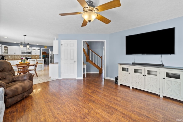2034 Windflower Pl, West Lafayette, IN 47906 - living room featuring wood finished floors, a ceiling fan, stairway, baseboards, and a chandelier