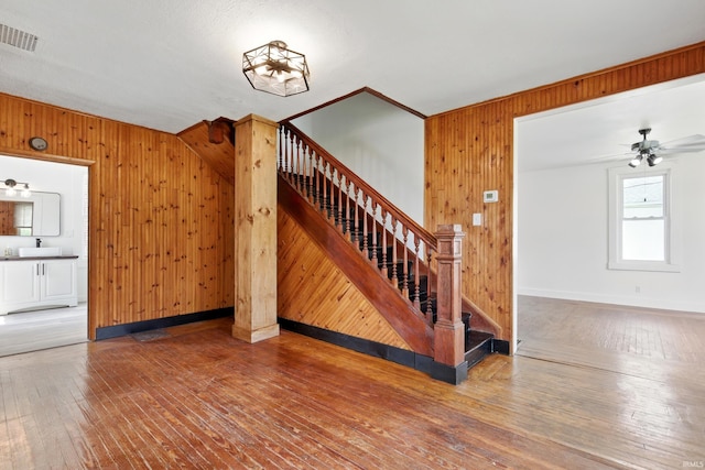 44 E Taylor St, Huntington, IN 46750 - unfurnished living room with wooden walls, wood-type flooring, stairway, a ceiling fan, and baseboards