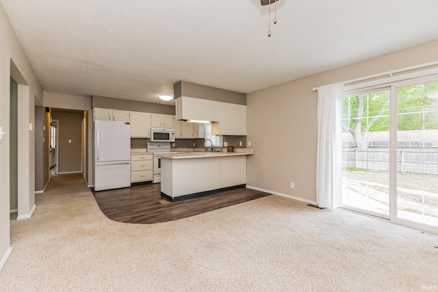 3608 W 31st St, Muncie, IN 47302 - kitchen featuring white appliances, dark colored carpet, baseboards, a peninsula, and light countertops