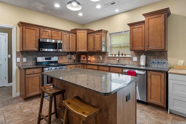 4665 S 150 E, Lafayette, IN 47909 - kitchen featuring stainless steel appliances, a sink, backsplash, a kitchen island, and brown cabinets