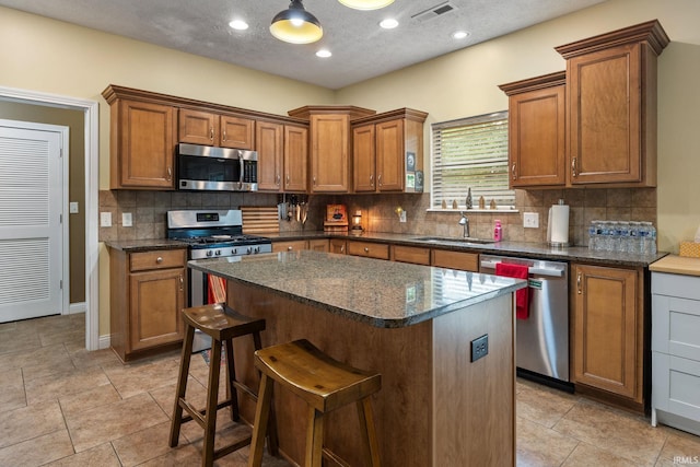 4665 S 150 E, Lafayette, IN 47909 - kitchen with stainless steel appliances, a sink, brown cabinetry, decorative backsplash, and a center island