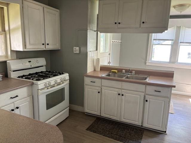 1515 E Donald St, South Bend, IN 46613 - kitchen with white range with gas stovetop, a sink, light wood-style flooring, white cabinetry, and light countertops