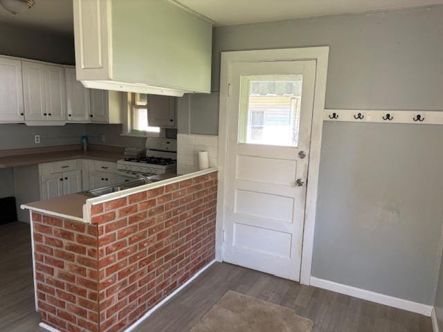 1515 E Donald St, South Bend, IN 46613 - kitchen with white gas range, white cabinets, wood finished floors, baseboards, and a peninsula