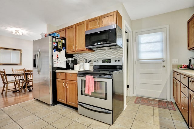 2012 Clayton Ave, Evansville, IN 47715 - kitchen featuring appliances with stainless steel finishes, light tile patterned floors, light countertops, and brown cabinetry