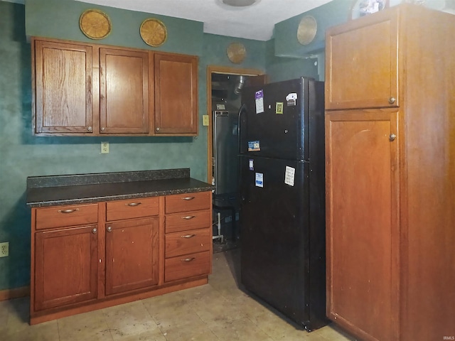 2550 N Kentucky Ave, Evansville, IN 47711 - kitchen featuring dark countertops, brown cabinetry, and freestanding refrigerator