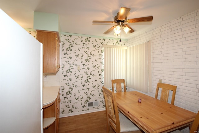 19511 Eaton Ave, South Bend, IN 46637 - dining space with a ceiling fan, wood finished floors, wallpapered walls, brick wall, and baseboards