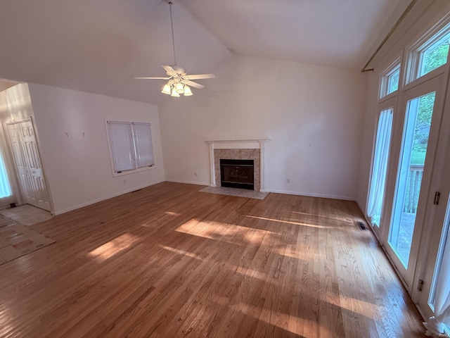 53172 Bracken Fern Dr, South Bend, IN 46637 - unfurnished living room featuring a tiled fireplace, light wood-style flooring, baseboards, ceiling fan, and high vaulted ceiling