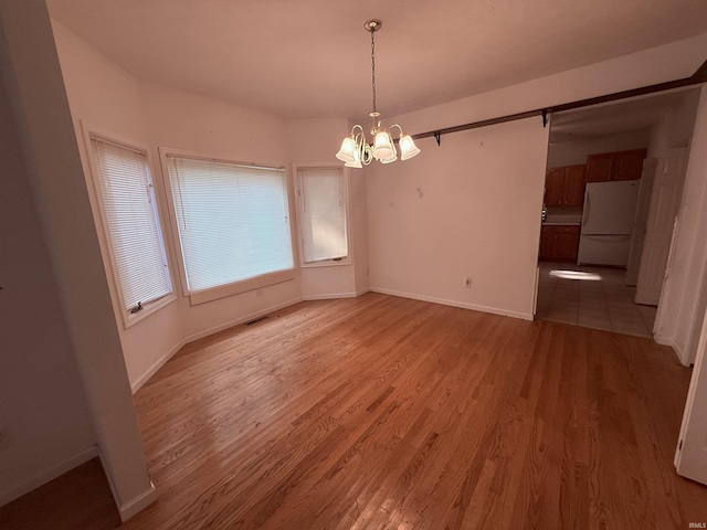 53172 Bracken Fern Dr, South Bend, IN 46637 - unfurnished dining area with a chandelier, light wood-type flooring, and baseboards