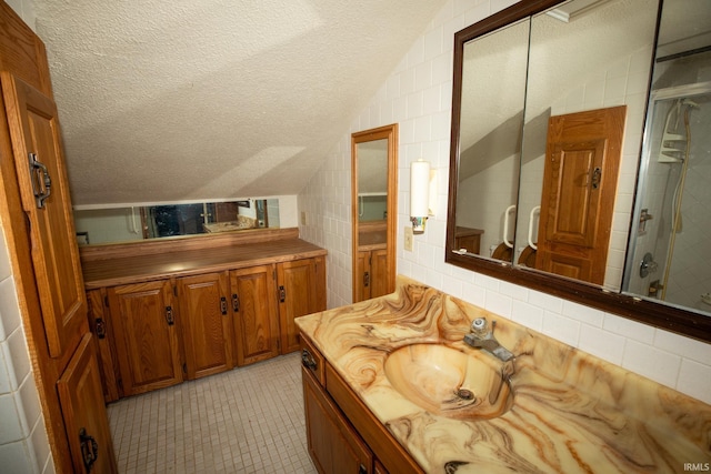 401 S Plymouth St, Culver, IN 46511 - bathroom featuring vanity, tiled shower, lofted ceiling, a textured ceiling, and decorative backsplash