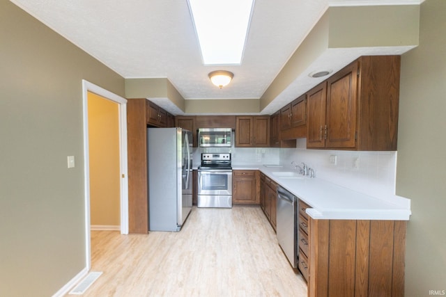 604 W Soutar Dr, Bloomington, IN 47403 - kitchen featuring stainless steel appliances, light wood finished floors, light countertops, a sink, and decorative backsplash