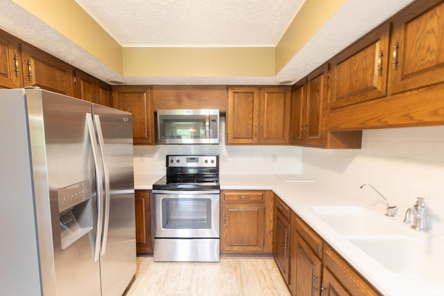 604 W Soutar Dr, Bloomington, IN 47403 - kitchen with appliances with stainless steel finishes, brown cabinetry, a textured ceiling, decorative backsplash, and light countertops
