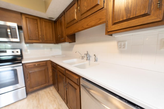 604 W Soutar Dr, Bloomington, IN 47403 - kitchen with appliances with stainless steel finishes, a sink, decorative backsplash, light countertops, and brown cabinetry