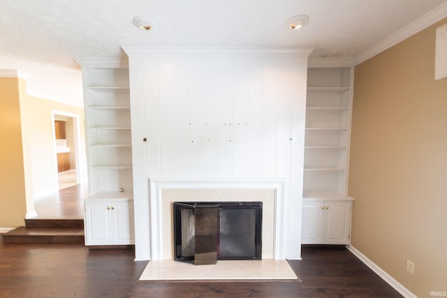 604 W Soutar Dr, Bloomington, IN 47403 - unfurnished living room featuring crown molding, built in features, dark wood-style flooring, a glass covered fireplace, and baseboards